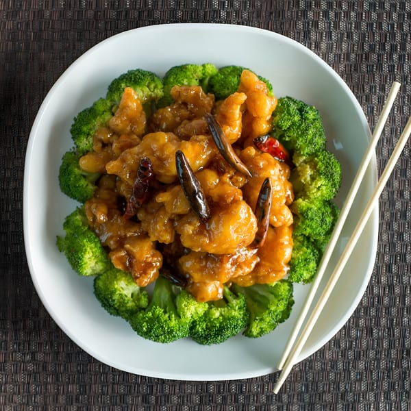 Dragon Dynasty Take Out's General Tso's chicken with broccoli and dried chilies, served with chopsticks.