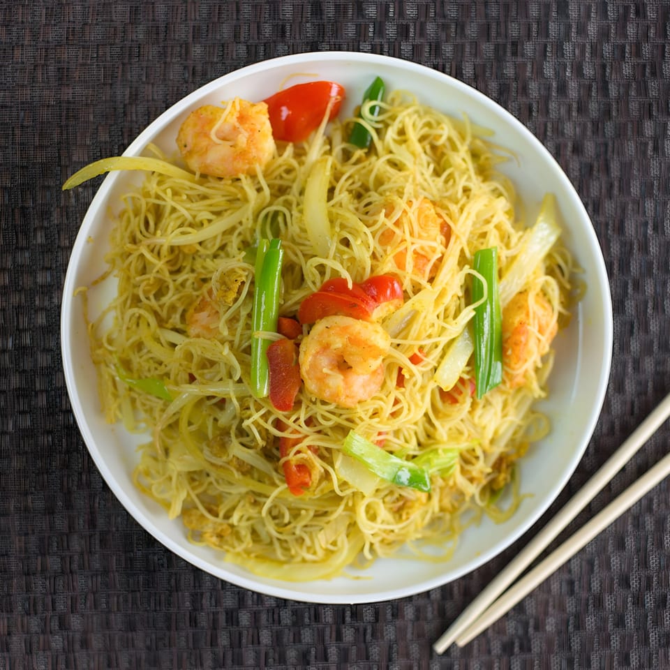 Dragon Dynasty Take Out's Singapore Mei Fun with shrimp, peppers, and scallions, served with chopsticks.